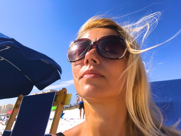 Foto close-up di una donna che indossa occhiali da sole contro il cielo
