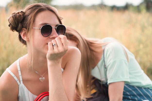 Close-up of woman wearing sunglasses sitting on field