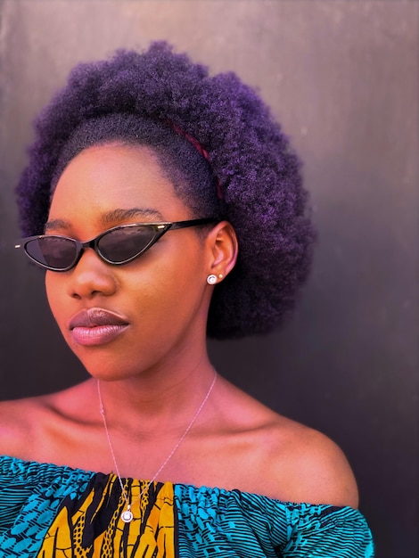 Photo close-up of woman wearing sunglasses standing against wall