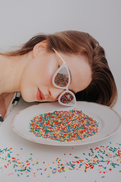 Photo close-up of woman wearing sunglasses with confetti against gray background