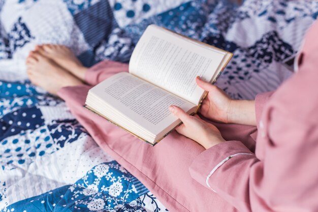 女性のクローズアップはパジャマを着て、家でリラックスして本を読んでいます。家にいる。検疫