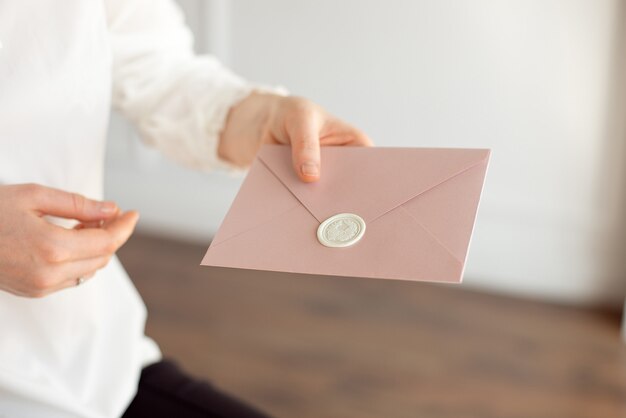 Il primo piano della donna in camicia bianca di stile di affari tiene in sua mano una carta dell'invito