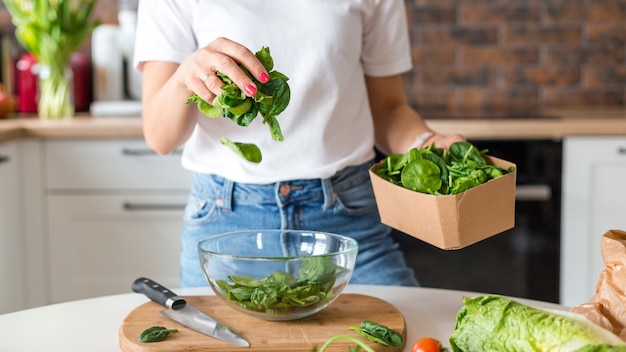 Chiuda sulla donna in t-shirt bianca che cucina insalata con effetto movimento a casa cucina. processo di cottura di cibi sani, concetto di insalata di verdure. menù, banner ricettario