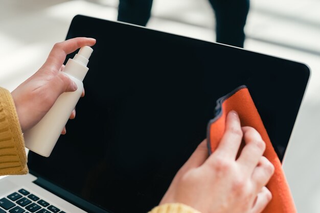 Foto avvicinamento. una donna che pulisce lo schermo del laptop con un tovagliolo antisettico.