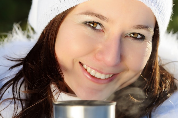 Foto close-up di donna con capelli castani, indossando abiti invernali bianchi con pelliccia