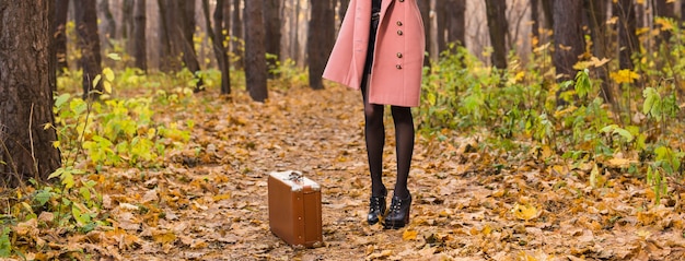 close up of woman with brown retro suitcase walking through the