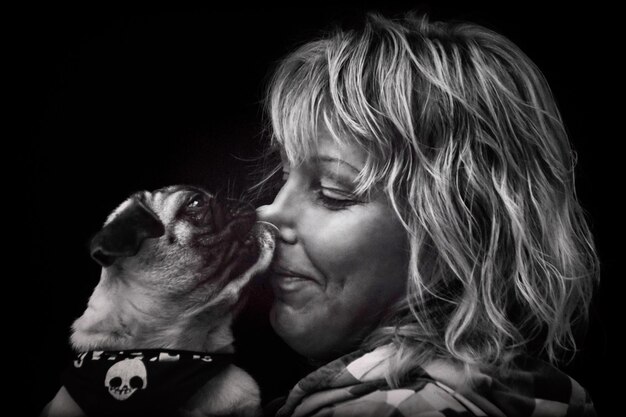 Close-up of woman with dog against black background