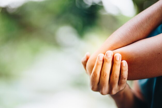 Photo close-up of woman with elbow pain while standing outdoors