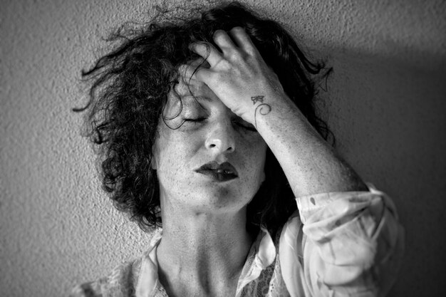 Photo close-up woman with hand in hair against wall