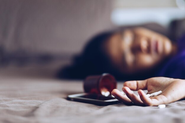 Photo close-up of woman with medicines lying at home