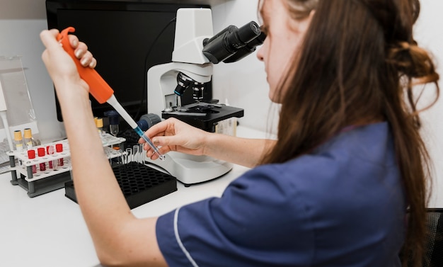 Foto donna del primo piano con il microscopio una pipetta