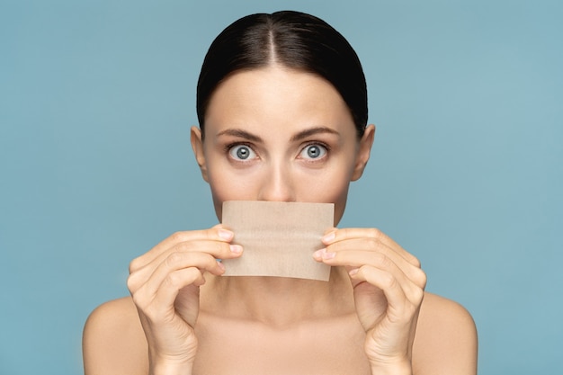 Primo piano di donna con trucco naturale del viso, tenendo la carta assorbente per il viso