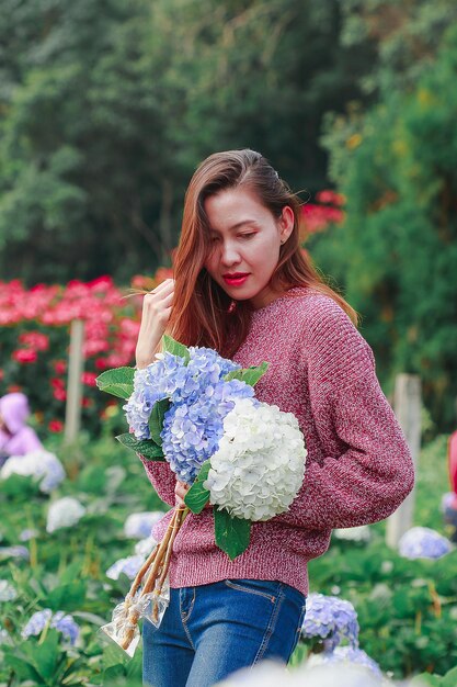 Close-up of woman with pink flower standing against plants