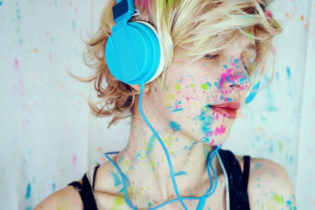 Close-up of woman with powder paint on her face listening music