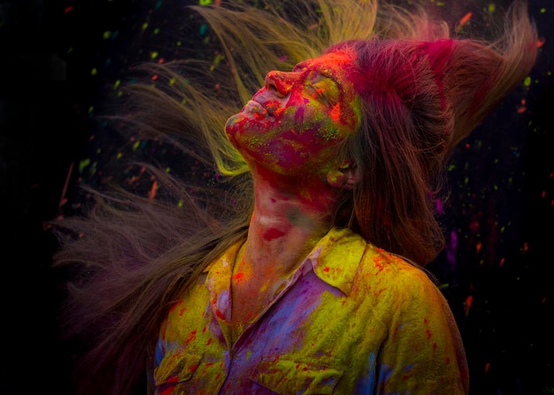 close-up of woman with powder paint tossing hair against black background