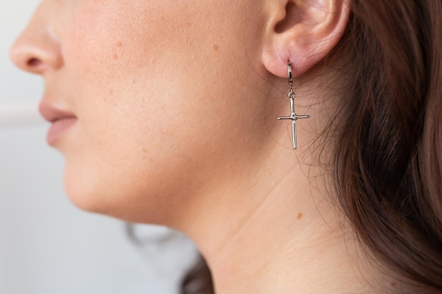 Close up woman with silver cross earrings Female jewelry and accessories