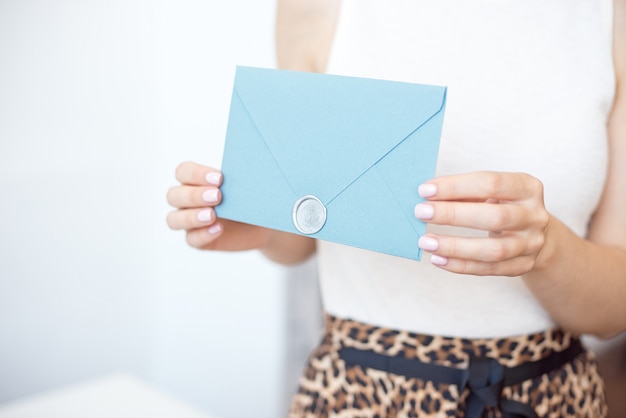 Foto donna del primo piano con l'ente esile che tiene in mano la carta della busta di forma quadrata di colore rosa blu della carta dell'invito