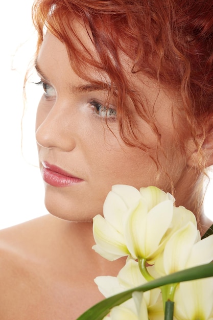 Foto close-up di una donna con fiori bianchi che guarda da un'altra parte