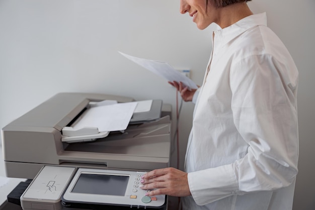 近代的なオフィスのコピー機でドキュメントをスキャンする女性労働者のクローズ アップ