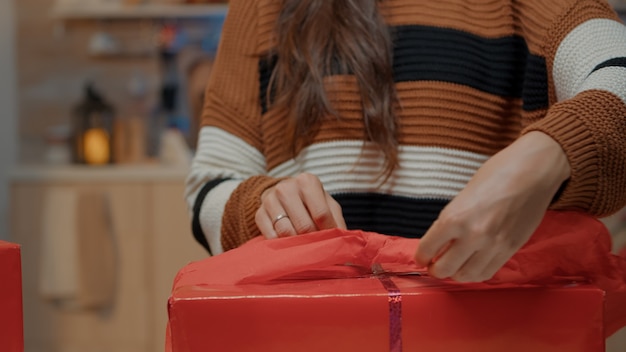 Close up of woman wrapping bow on gift for friends