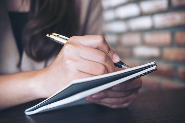 Foto close-up di una donna che scrive in un libro sul tavolo