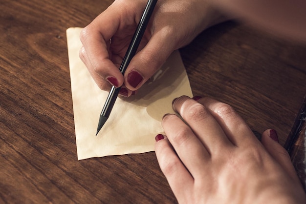 Foto close-up di una donna che scrive su carta al tavolo