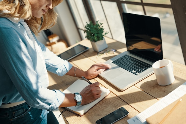 Close up of woman writing something down while working in the office