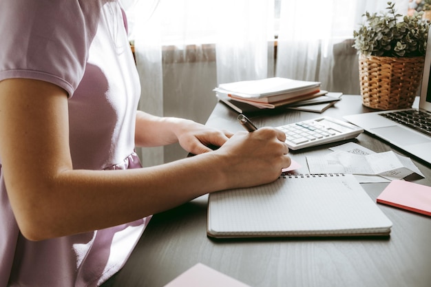 Close up of a woman writing something on the paper in office