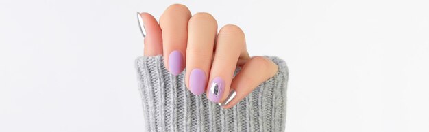 Close up womans hand with matte lavender and silver nails in sweater