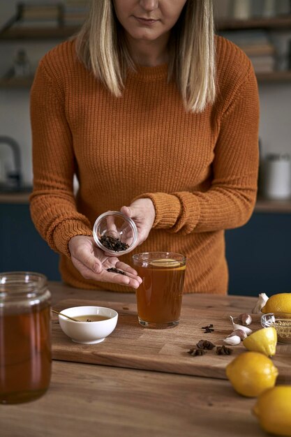 Photo close up of womans hands adding cloves to the tea