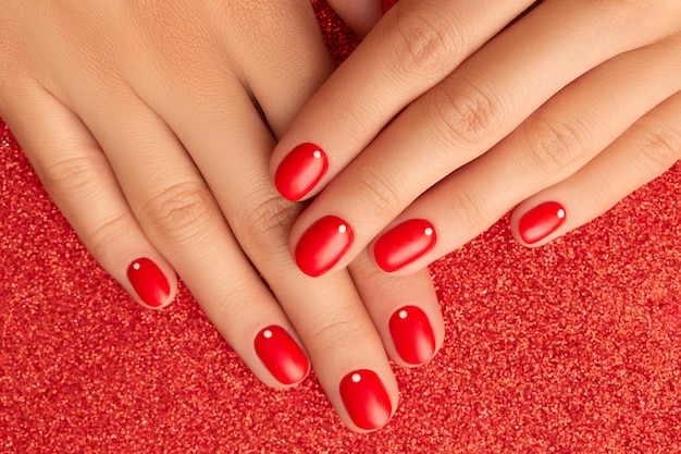 Close up womans hands with red minimalist nail design. manicure, pedicure beauty salon concept. new year christmas sale