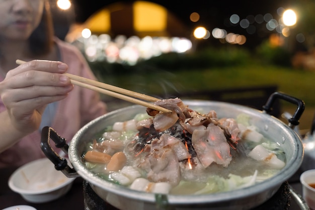 ボケ味の背景でバーベキュー豚肉を食べる女性のクローズアップ