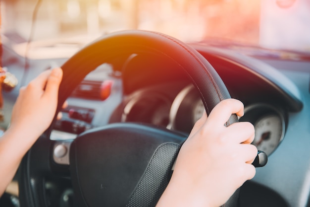 Close up women hand driving city car in hot summer day