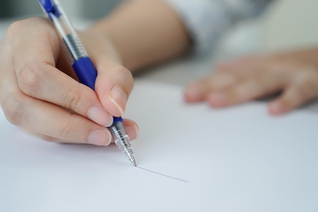 Foto chiuda sulla penna della tenuta della mano delle donne alla carta