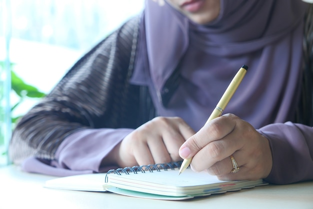 Close up of women hand writing on notepad.