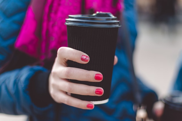 Chiuda in su delle mani delle donne che tengono la tazza di caffè di carta