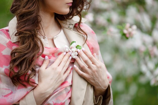 Blosson 사과 나무의 분 지와 여자 손을 닫습니다. 봄 시간에 꽃 사과 나무 정원에서 아름 다운 갈색 머리 젊은 여성.