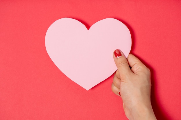 Photo close up women holding pink blank paper with heart shape on white