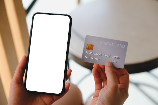 Close up of women's hands holding cell telephone and credit card with blank copy space