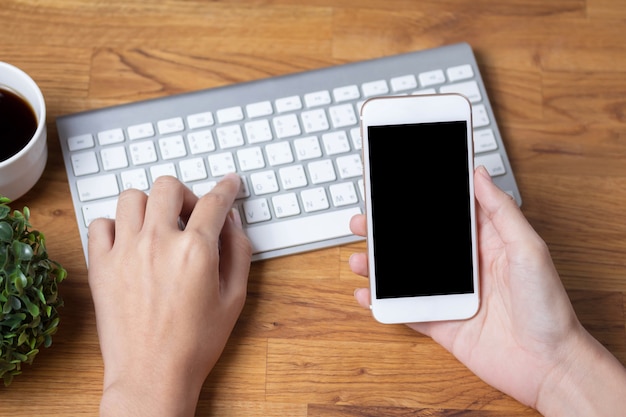 Chiuda su delle mani delle donne che tengono il telefono delle cellule con il ghiaione dello spazio in bianco della copia