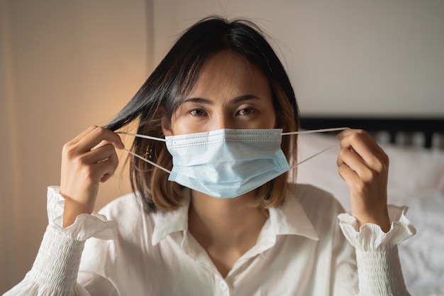 Close up women wearing surgical mask in the bedroom