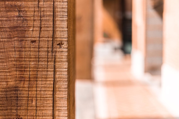 Close up of wood column showing wood grain and texture against blurred hallway background