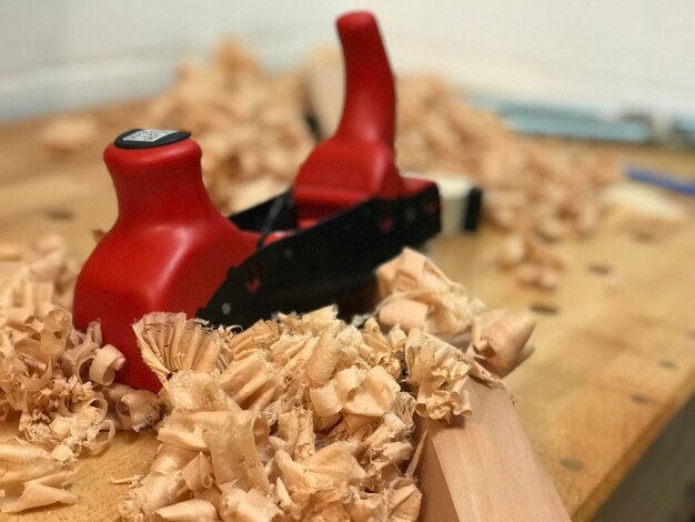 Close-up of wood shavings and plane on workbench at workshop