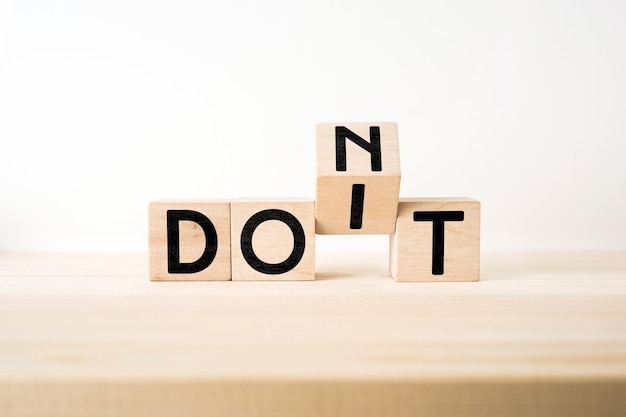 Photo close-up of wooden blocks with dont dint text on table against white background