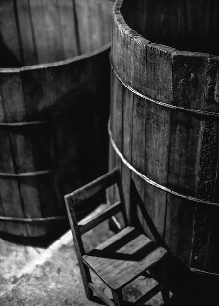 Photo close-up of wooden chair by barrels