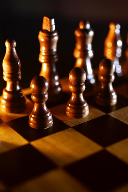 Close-up of wooden chess on a chessboard at night.