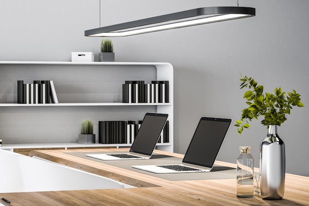 Close up of wooden desk with empty mock up laptops decortaive and other items in concrete office interior 3D Rendering