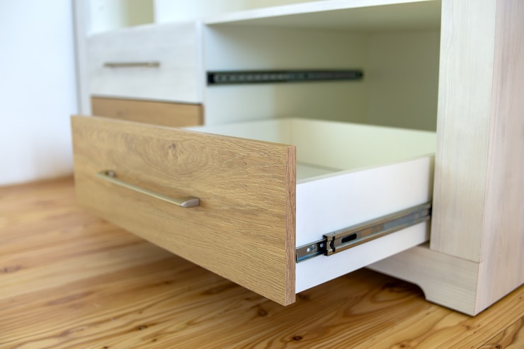 Photo close up of wooden drawer in contemporary cupboard cabinet.