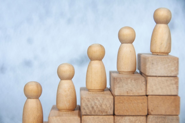 Close up of wooden figure on top of stacking cubes representing goal achievement Goal achievement and leadership concept