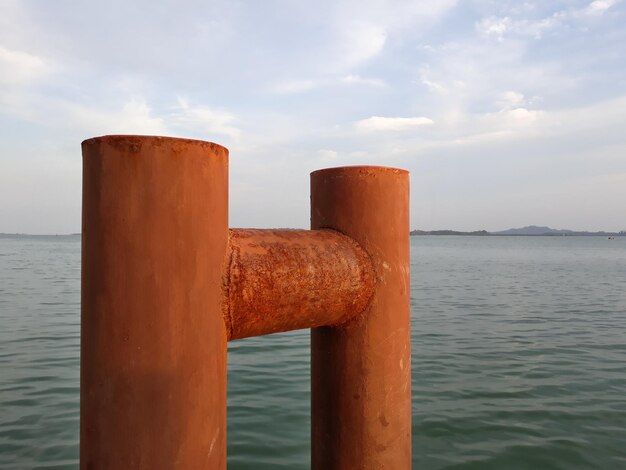 Close-up of wooden post in sea against sky